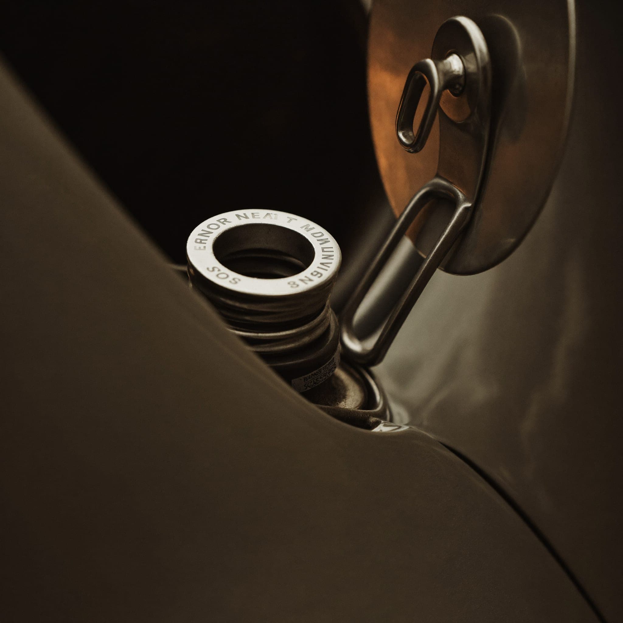 Brushed metal fuel filler neck of a classic sports car in warm close-up