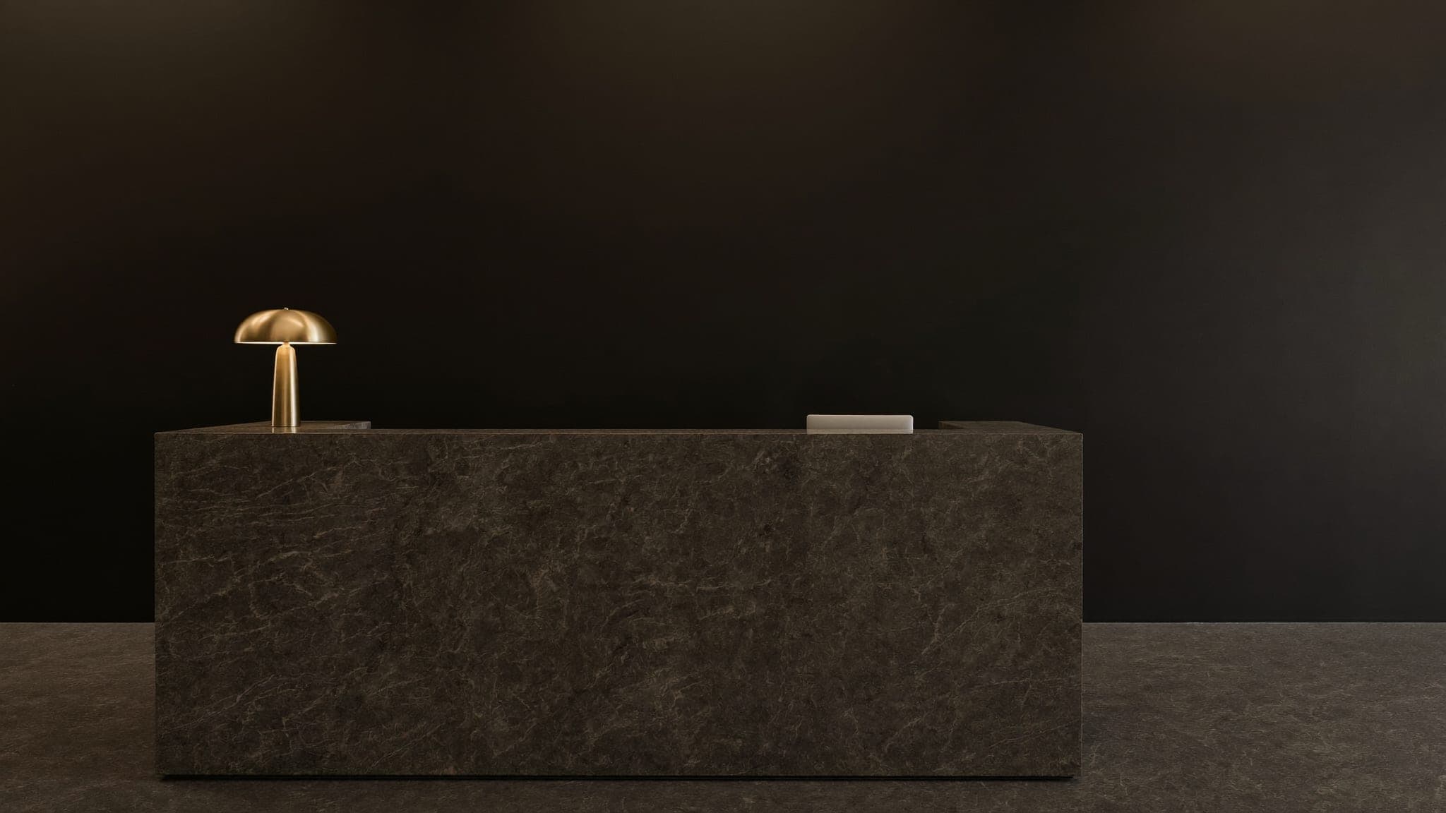 Dark stone reception desk with a single brass lamp at the Vault 620 private facility