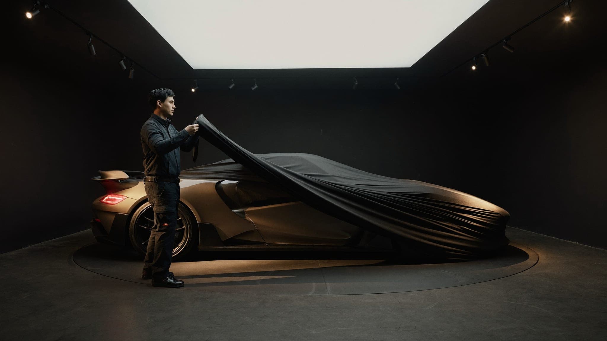 Technician lifting a black fitted cover from a pristine sports car in the Vault 620 gallery