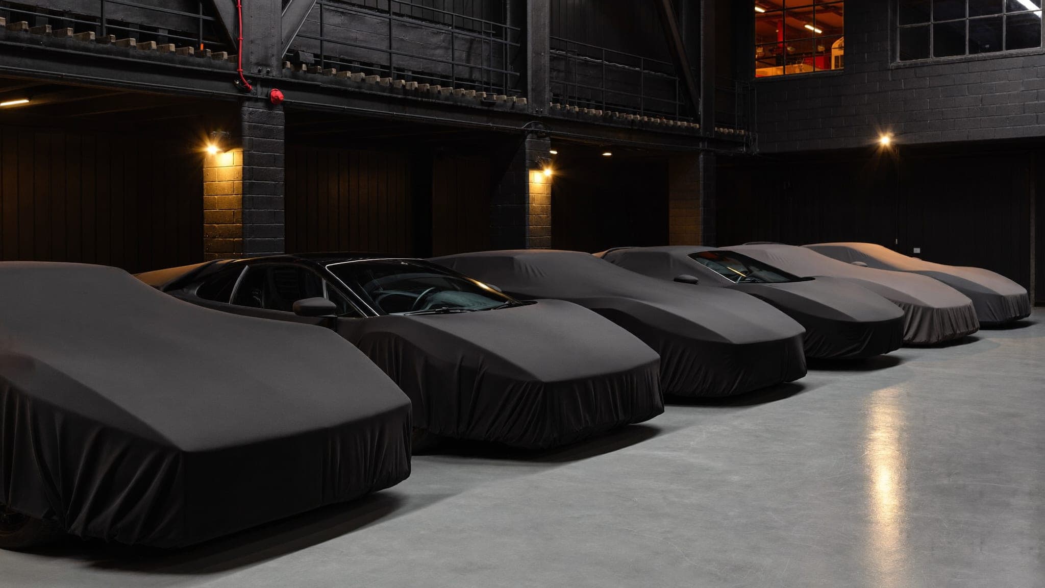Row of covered and uncovered collector cars inside the Vault 620 preservation gallery