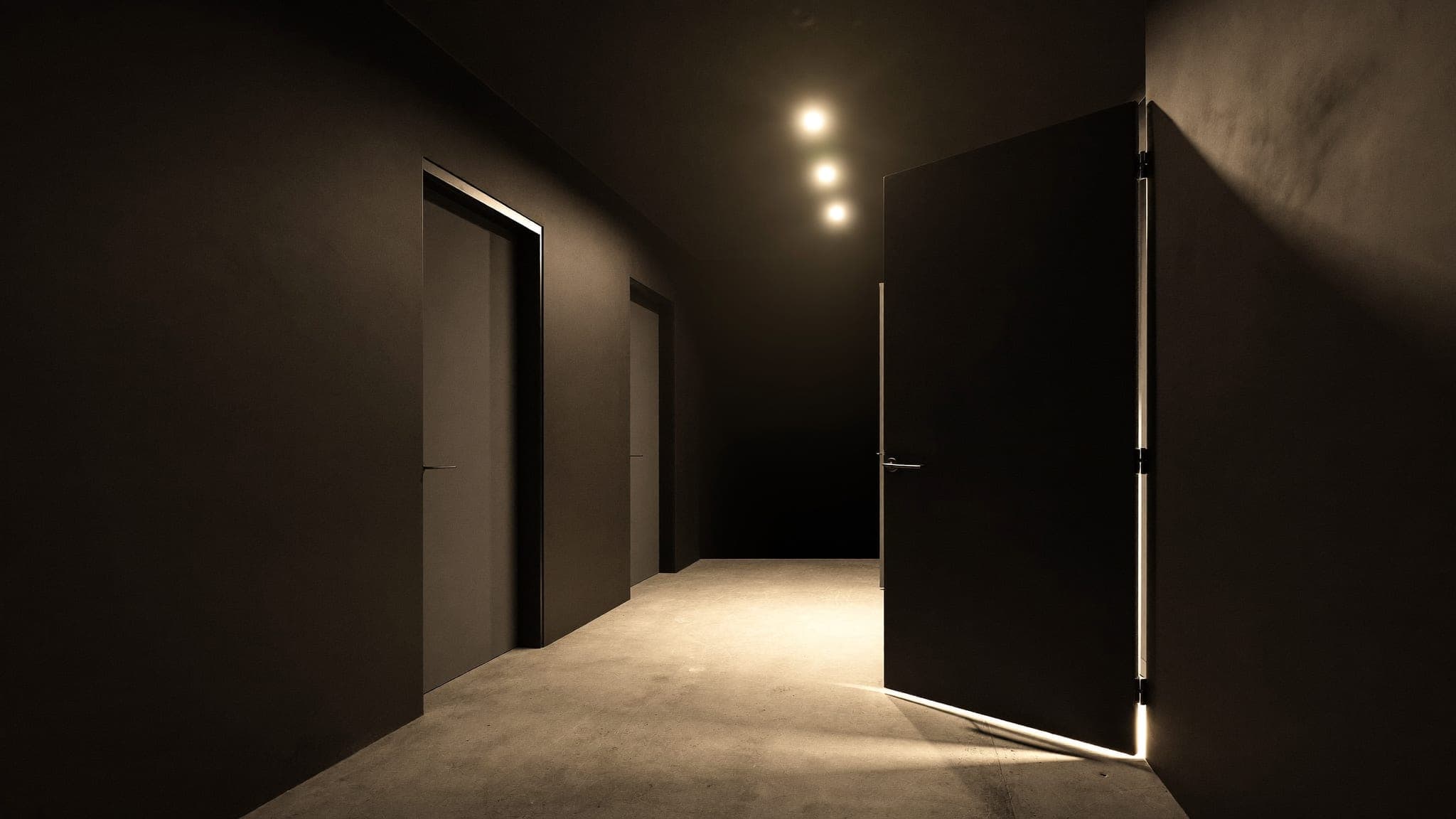Corridor of closed private storage bay doors under warm downlights at Vault 620